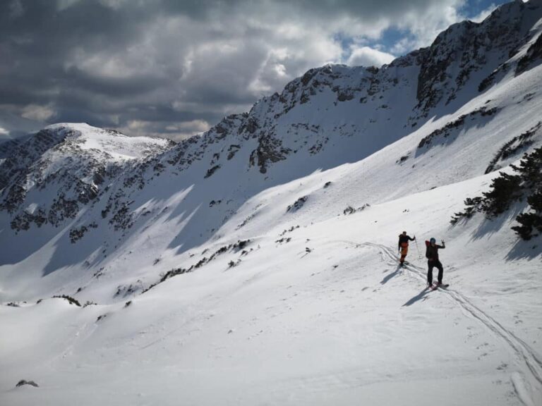 Two off-piste freeriders heading up the mountain in the snow